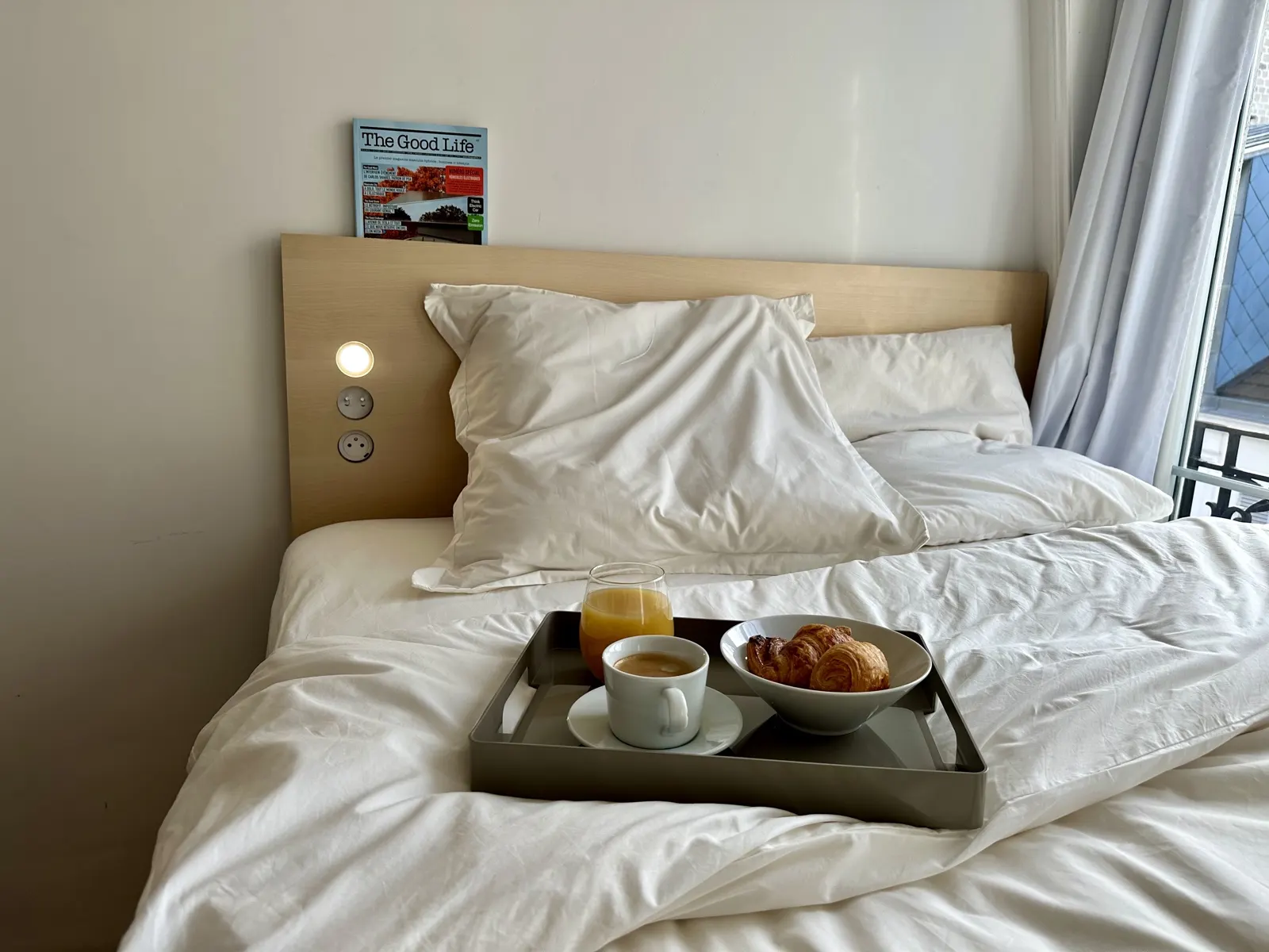 Chambre de bonne rénovée par Welcome to the City rue de l'Abbé Groult à Paris 15e : lit sur socle, tête de lit en bouleau, plateau du petit-déjeuner