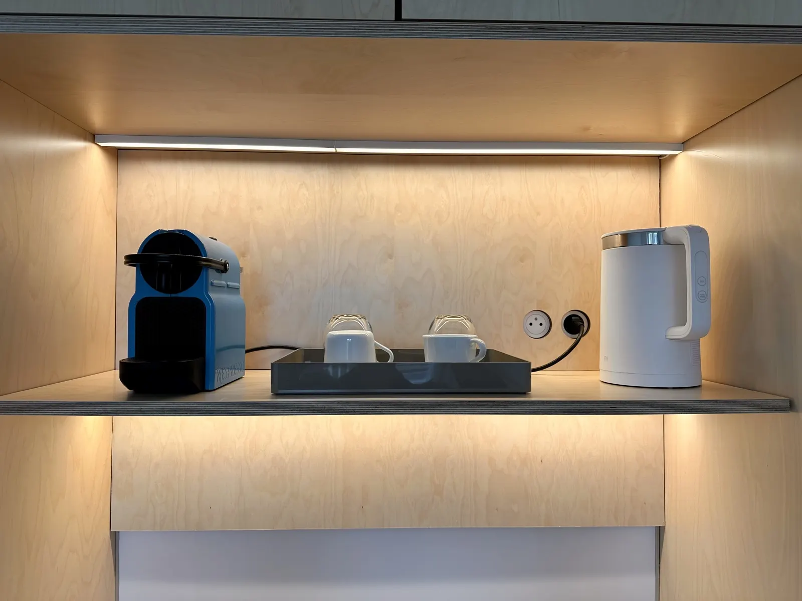 Kitchenette intégrée avec machine à café et bouilloire sous un bandeau LED