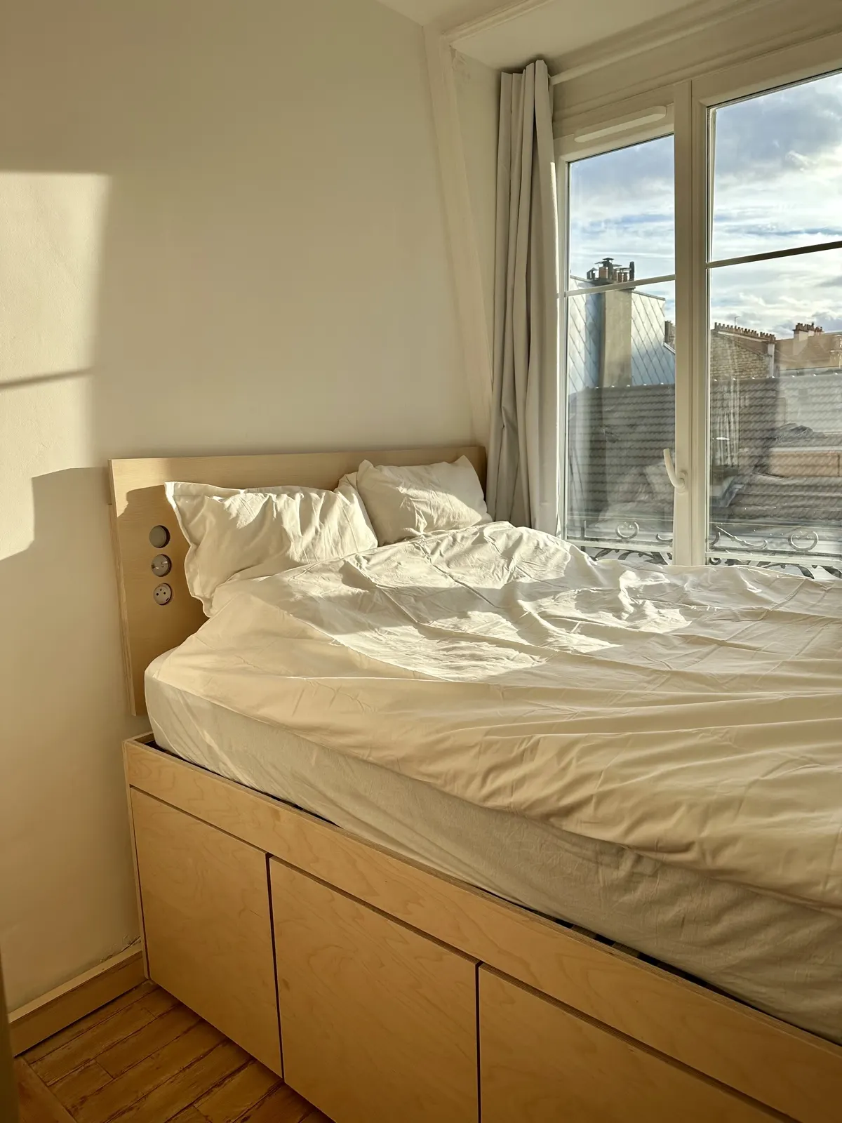Lit double sur socle avec tiroirs, face à la fenêtre, chambre rénovée rue de l'Abbé Groult à Paris 15e